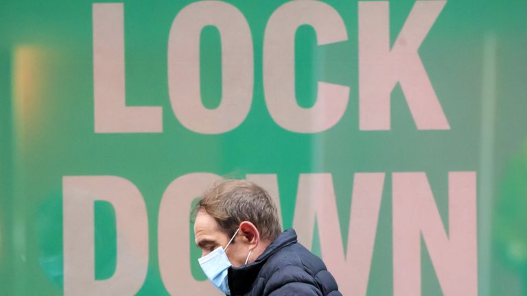 A man walks past a poster in the window of a Primark shop in Manchester, in the final week of a four week national lockdown to curb the spread of coronavirus.