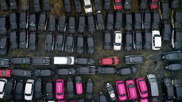 A staff member walks through unused black cabs parked in a large area of farmland in Epping Forest, which is being rented by GB Taxi Services to store their large fleet of London taxis that are no longer being used due to a severe drop in demand as coronavirus restrictions continue to reduce travel and office working.
