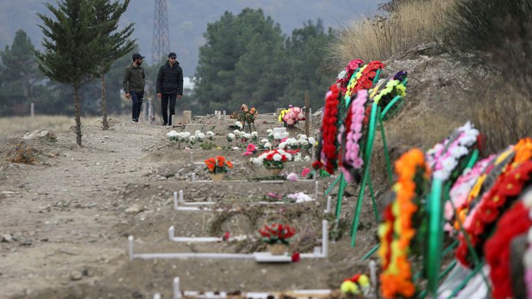 Men walk along graves of soldiers and civilians who were killed during a military conflict over the breakaway region of Nagorno-Karabakh, in Stepanakert