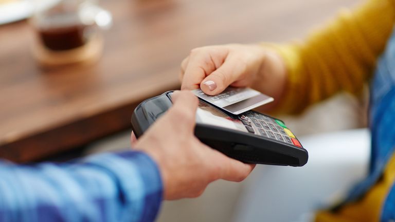 Close-up of unrecognizable customer choosing contactless payment using credit card while waitress accepting payment over nfc technology (Close-up of unrecognizable customer choosing contactless payment using credit card while waitress accepting paymen