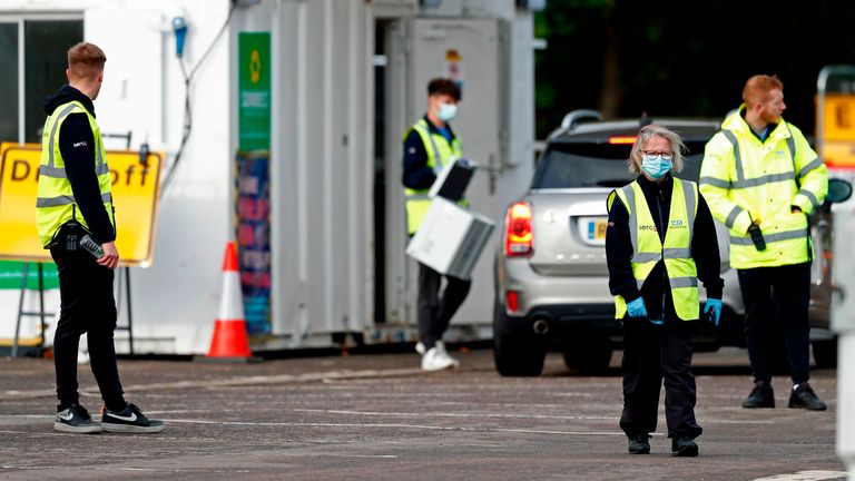 Workers wearing high-vis jackets with SERCO and NHS Test and Trace logos on, advise drivers attending a novel coronavirus COVID-19 drive-in testing facility set up at the Chessington World of Adventures Resort, in Chessington, southwest of London, on October 20, 2020.