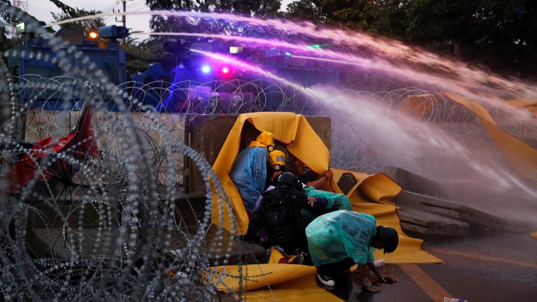 Demonstrators take cover from water cannons behind a barricade during an anti-government protest as lawmakers debate on constitution change, outside of the parliament in Bangkok, Thailand, November 17, 2020. REUTERS/Jorge Silva
