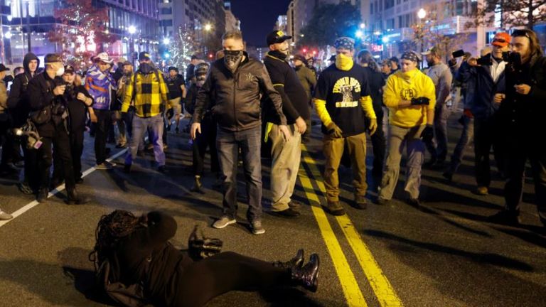 A woman lies on the ground surrounded by members of far-right militia Proud Boys (Pic: Reuters//Carlos Barria)