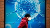 A man wearing a protective face mask walks past an illustration of a virus outside a regional science centre, as the city and surrounding areas face local restrictions in an effort to avoid a local lockdown being forced upon the region, amid the coronavirus disease (COVID-19) outbreak, in Oldham, Britain August 3, 2020