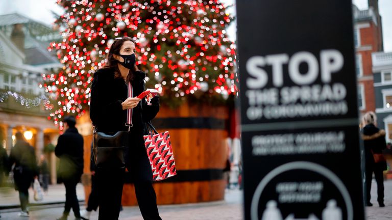 A pedestrian wearing a protective face covering to combat the spread of the coronavirus, walks past the Christmas tree in Covent Garden in central London on November 27, 2020, as life under a second lockdown continues in England. - England will return to a regional tiered system when the national stay-at-home order ends on December 2, and 23.3 million residents in the worst-hit areas are set to enter the "very high" alert level. (Photo by Tolga Akmen / AFP) (Photo by TOLGA AKMEN/AFP via Getty Images)