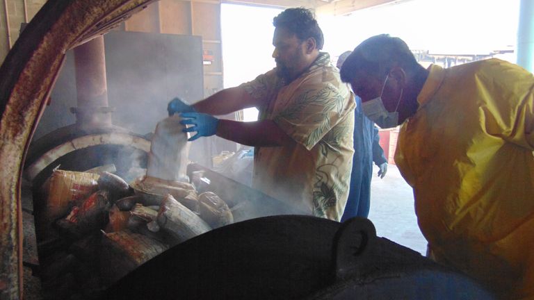 A photo on December 15, 2020 shows Marshall Islands Police Captain Eric Jorban, (L), emptying one-kilo packages of cocaine into an incinerator in Majuro from an 18-foot fiberglass boat washed up on Ailuk Atoll, a remote atoll with about 400 people, in the Marshall Islands last week with 649 kilos (1,340 pounds) of cocaine sealed in its hold under the deck. (Photo by Giff JOHNSON / AFP) (Photo by GIFF JOHNSON/AFP via Getty Images)