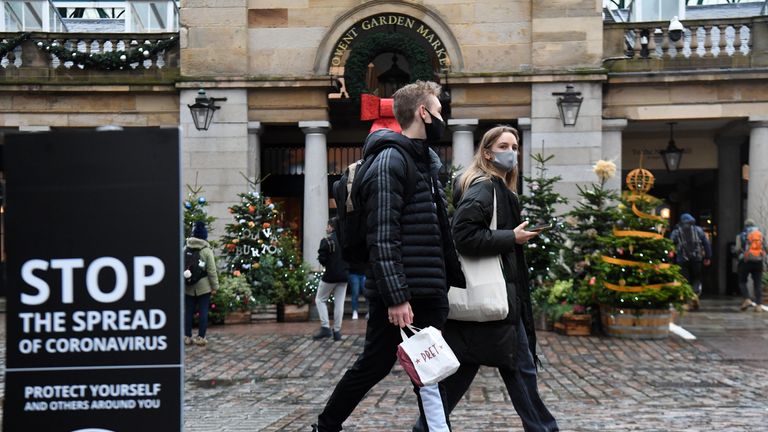 People walk past a sign advising social distancing in Covent Garden in London.