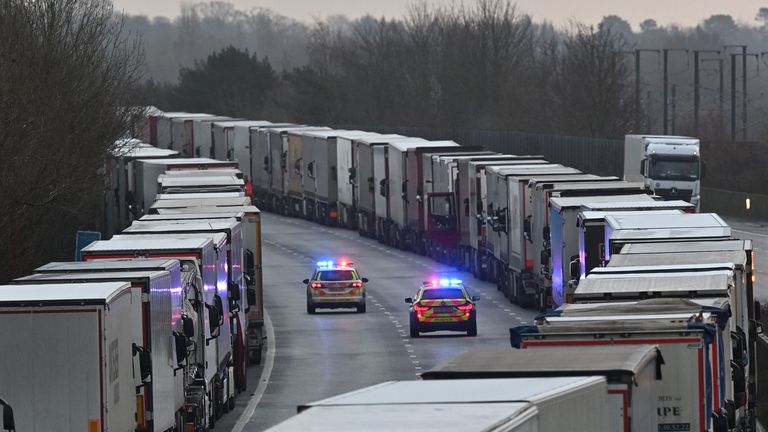 Police cars patrol as freight lorries and goods vehicles queue on a closed section of the M20 motorway which leads to the Port of Dover, near Ashford in Kent, south east England on December 22, 2020, after a string of countries banned travel including accompanied freight arriving from the UK, due to the rapid spread of a more-infectious new coronavirus strain. - Britain's critical south coast port at Dover said on December 20 it was closing to all accompanied freight and passengers due to the French border restrictions "until further notice". (Photo by JUSTIN TALLIS / AFP) (Photo by JUSTIN TALLIS/AFP via Getty Images)