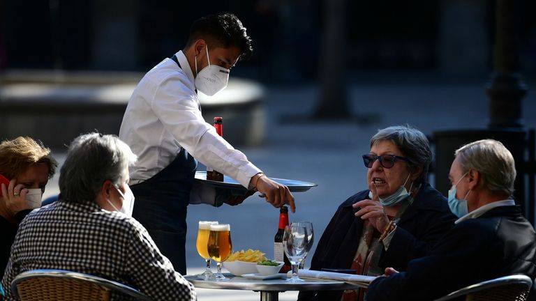 A waiter serves customers at a restaurant in Barcelona on November 23, 2020 as bars, restaurants and movie theatres were allowed to reopen in Spain&#39;s northeastern region of Catalonia after being closed for over a month as part of measures to slow coronavirus infections. (Photo by LLUIS GENE / AFP) (Photo by LLUIS GENE/AFP via Getty Images)
