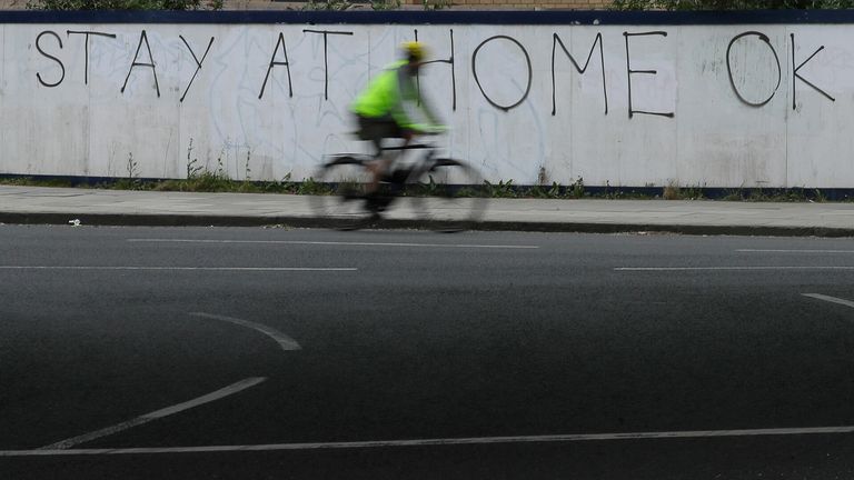 A cyclist moves past coronavirus graffiti. 
