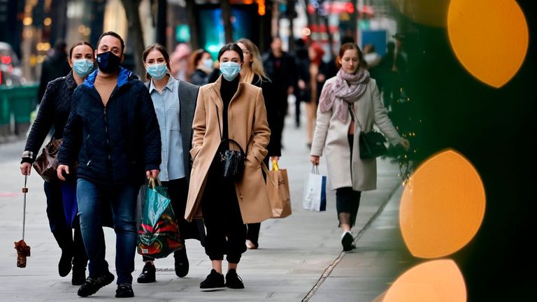 Pedestrians wearing a face mask or covering due to the COVID-19 pandemic, walk along Oxford Street in central London on December 22, 2020. - UK government borrowing continued to soar in November on emergency action to support the virus-hit economy which nevertheless rebounded stronger than expected in the third quarter, official data showed Tuesday.