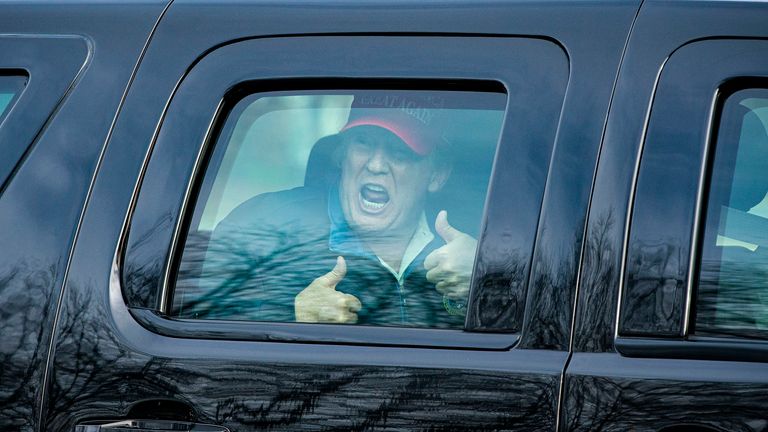 Donald Trump gives a thumbs up towards supporters as he leaves Trump National Golf Club