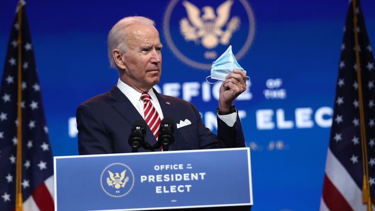 U.S. President-elect Joe Biden holds up a face mask as he delivers remarks about the U.S. economy during a press briefing at the Queen Theater on November 16, 2020 in Wilmington, Delaware