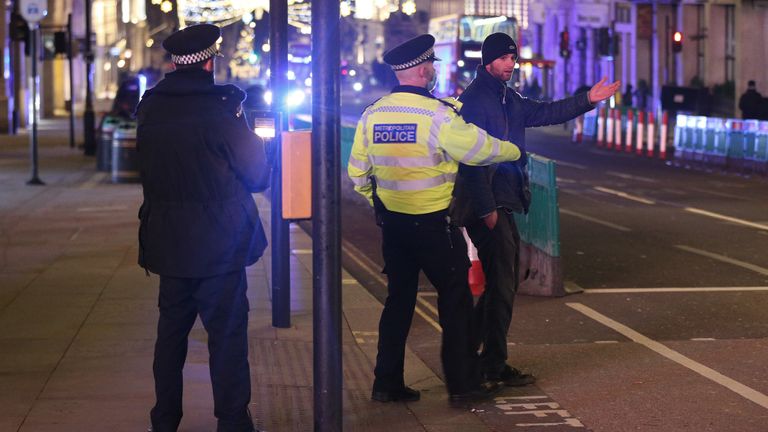 Police next to the statue of Eros in Piccadilly ask a man to move along