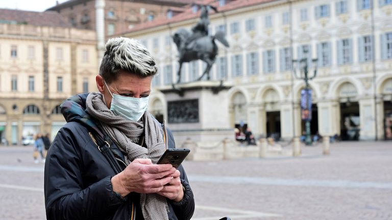 Une femme portant un masque de protection utilise son téléphone portable, alors qu'une épidémie de coronavirus continue de croître dans le nord de l'Italie, à Turin, en Italie, le 27 février 2020