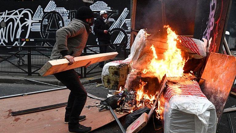 A protester throws wood on a barricade during demonstrations in Paris