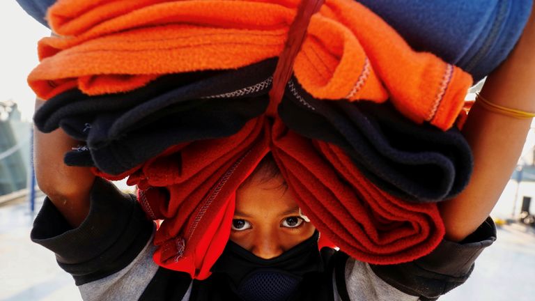 A Rohingya girl carries blankets as she prepares to board a ship to move to Bhasan Char island near Chattogram