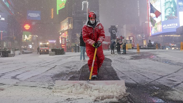 A worker clears snow as snow begins to fall in Times Square in New York City, New York