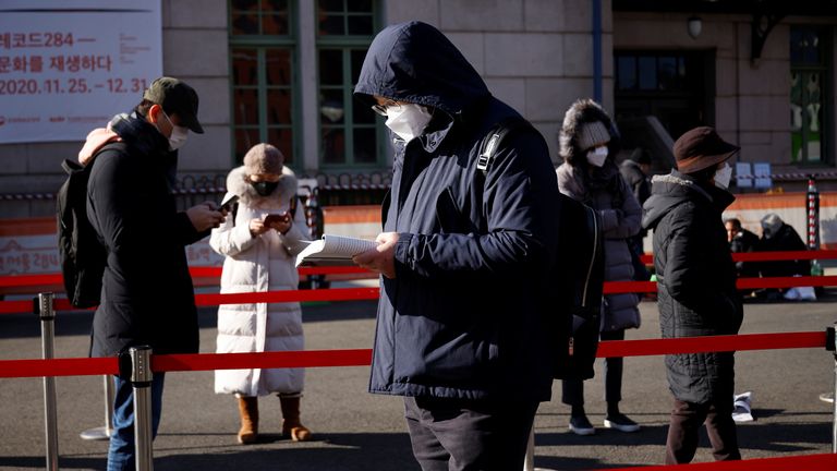 A man reads a book while waiting in a line to undergo coronavirus disease (COVID-19) test at a coronavirus testing site which is temporarily set up in front of a railway station on Christmas day in Seoul, South Korea, December 25, 2020. REUTERS/Kim Hong-Ji