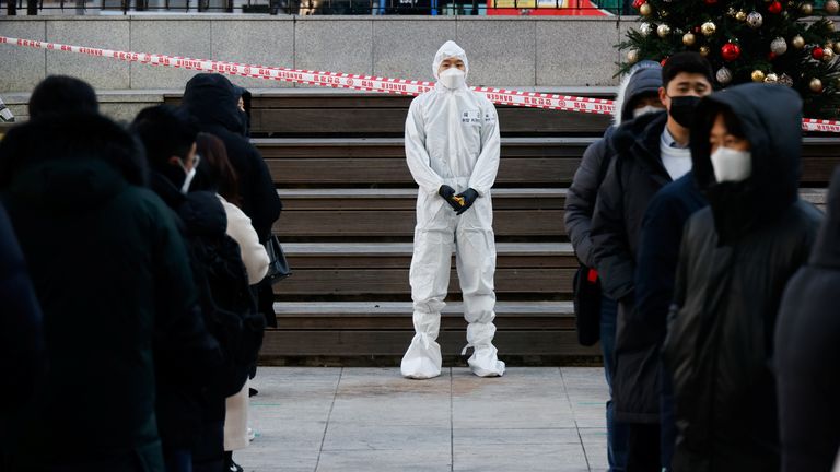 A South Korean soldier wearing a protective suit guides people who wait in a line to undergo a coronavirus disease (COVID-19) test at a coronavirus testing site which is temporarily set up near a subway station in Seoul, South Korea, December 17, 2020.