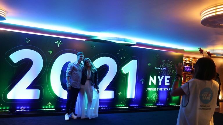 People begin celebrating New Year&#39;s Eve at the Sydney Harbour waterfront in Sydney
A man and woman pose for a photo in front of a 2021 sign as a limited number of people begin celebrating New Year&#39;s Eve at the Sydney Harbour waterfront amidst tightened COVID-19 prevention regulations in Sydney, Australia, December 31, 2020. REUTERS/Loren Elliott