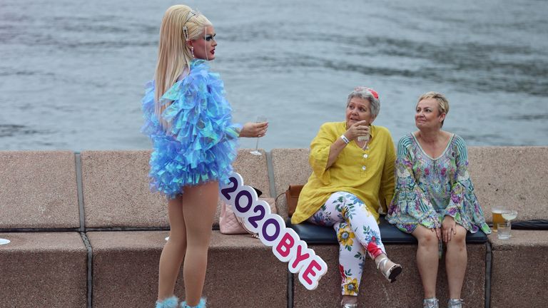 People begin celebrating New Year&#39;s Eve at the Sydney Harbour waterfront in Sydney
A reveller holds a sign reading "2020BYE" as a small number of people begin celebrating New Year&#39;s Eve at the Sydney Harbour waterfront amidst tightened COVID-19 prevention regulations in Sydney, Australia, December 31, 2020. REUTERS/Loren Elliott