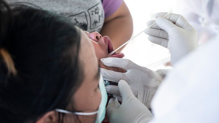 A health worker performs a Covid-19 swab test to a child with help from adults on December 25, 2020 in Bangkok, Thailand. Thailand&#39;s total number of confirmed Covid-19 infections soared to cross the 5,000 mark this week, following a major outbreak centered around Samut Sakhon province