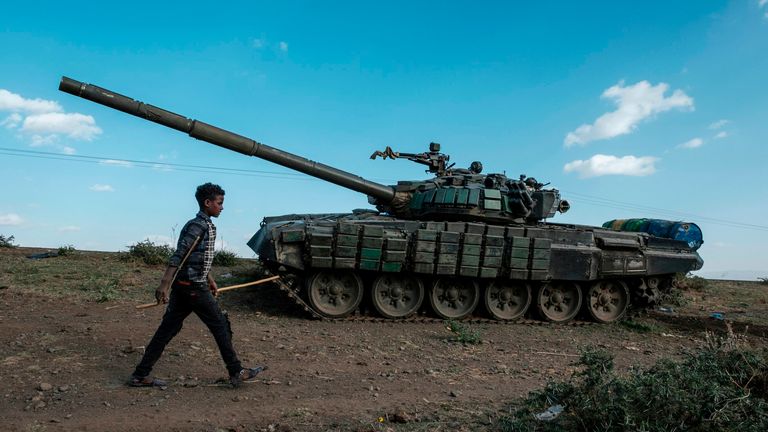 A shepherd walks in front of an abandoned tank belonging to Tigrayan forces in Ethiopia
