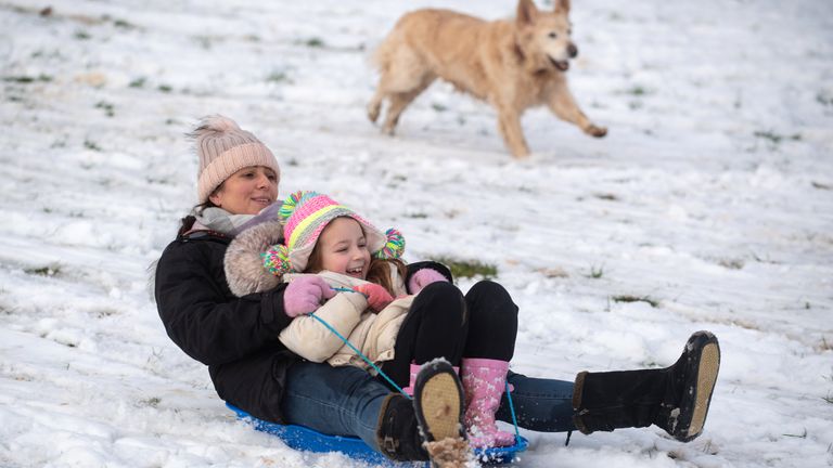 Lizzy and daughter Connie, 6, are chased down a snow covered hill by their golden retriever Pippa in a park in Newcastle-under-Lyme, Staffordshire.