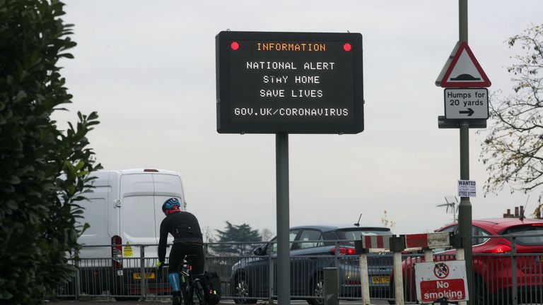A cyclist passes an information sign in Staines-upon-Thames, Surrey, advising to stay at home and save lives in the final week of a four week national lockdown to curb the spread of coronavirus.