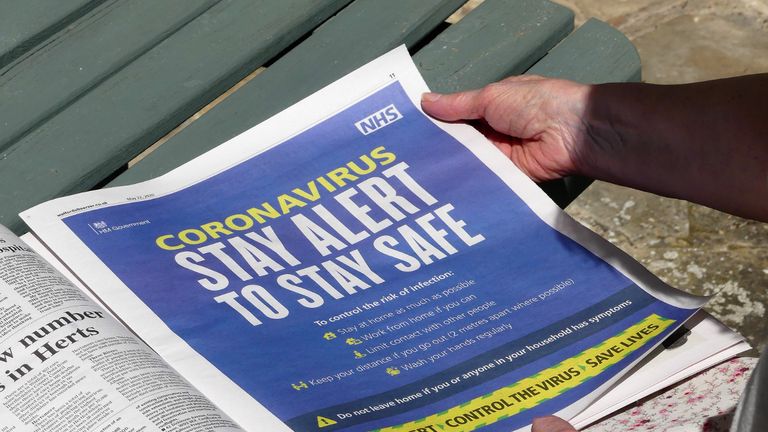 Chorleywood, Hertfordshire, England, UK - May 22nd 2020: Elderly woman reading Coronavirus Stay Alert to Stay Safe advertisement, issued by HM Government and NHS, in local newspaper