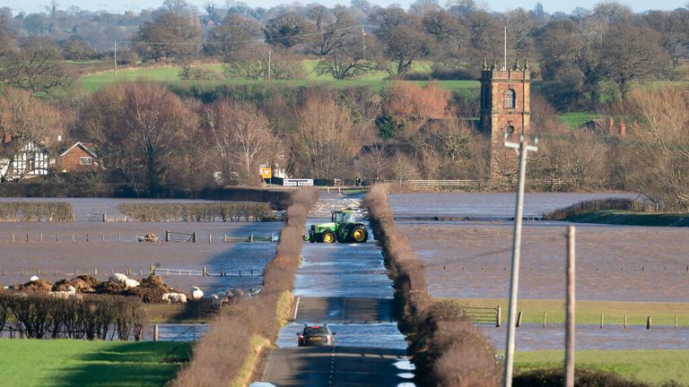A tractor attempts to negotiate flood waters at Bangor-on-Dee, Wales. Pic: Associated Press