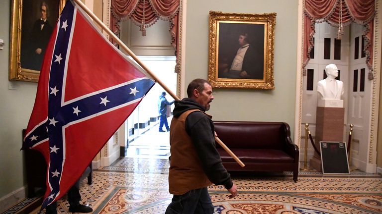 A supporter of President Donald Trump carries a Conferderate battle on the second floor of the U.S. Capitol near the entrance to the Senate after breaching security defenses, in Washington, U.S., January 6, 2021. REUTERS/Mike Theiler