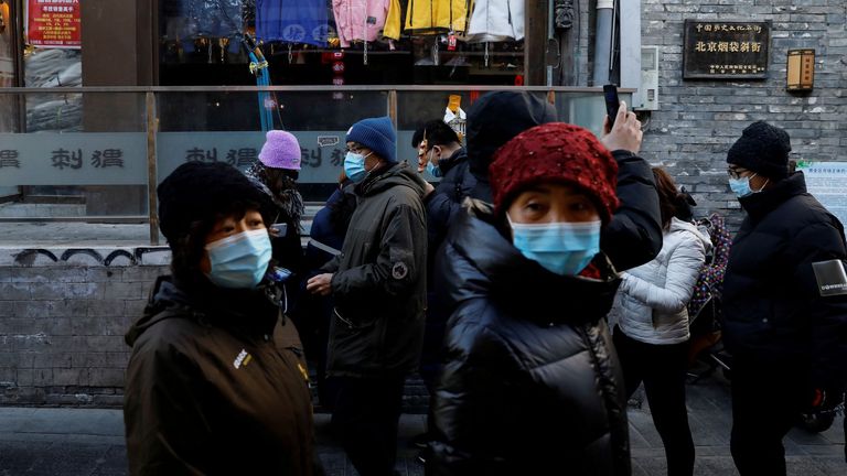 People wearing face masks following the coronavirus disease (COVID-19) outbreak walk past shops along Yandaixiejie alley, in Beijing, China January 16, 2021. 