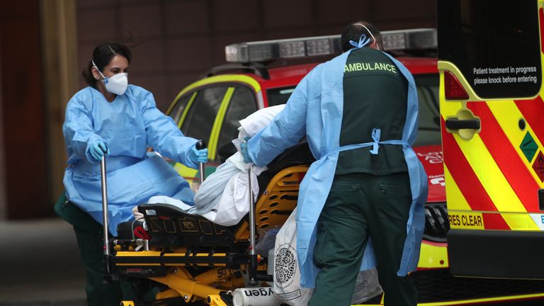 Paramedics transport a patient on a gurney outside the Royal London Hospital