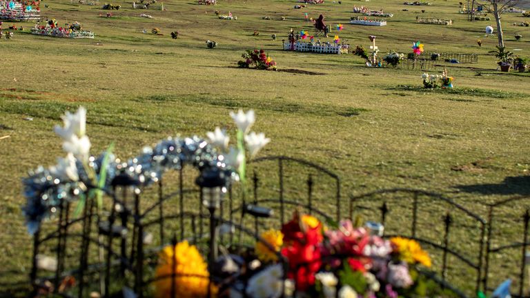 A mourner pauses at new grave sites at the biggest cemetery in North America as it struggles under a backlog of coronavirus-related burials, with the usual 5-7 day wait period after death now stretched to more than a month at Rose Hill Memorial Park and Mortuary, during the outbreak of the coronavirus disease (COVID-19) in California, U.S., January 26, 2021. Picture taken January 26, 2021. REUTERS/Mike Blake