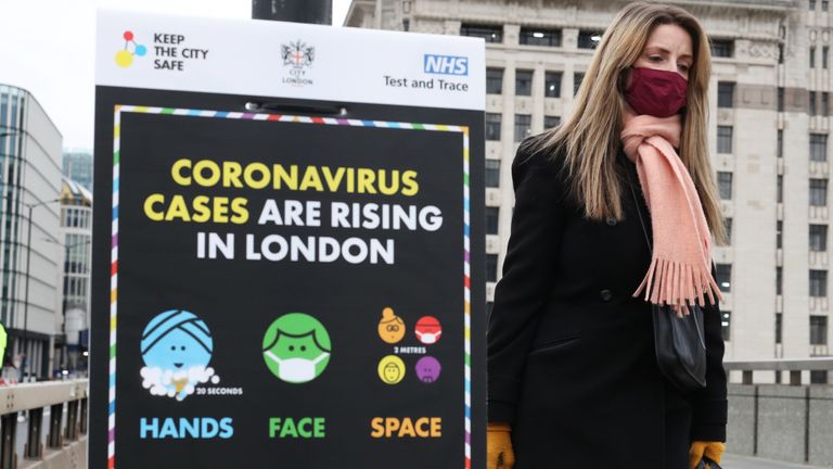 A woman walks past a coronavirus information sign outside London Bridge station, the morning after Prime Minister Boris Johnson set out further measures as part of a lockdown in England in a bid to halt the spread of coronavirus.