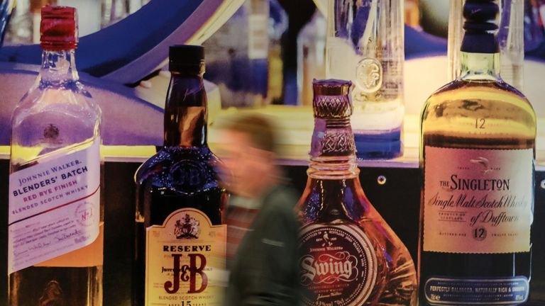 A person walks past Diageo owned whiskies on a poster at their headquarters in Edinburgh
