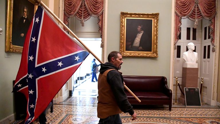 A supporter of Donald Trump carries a Confederate battle flag in the US Capitol