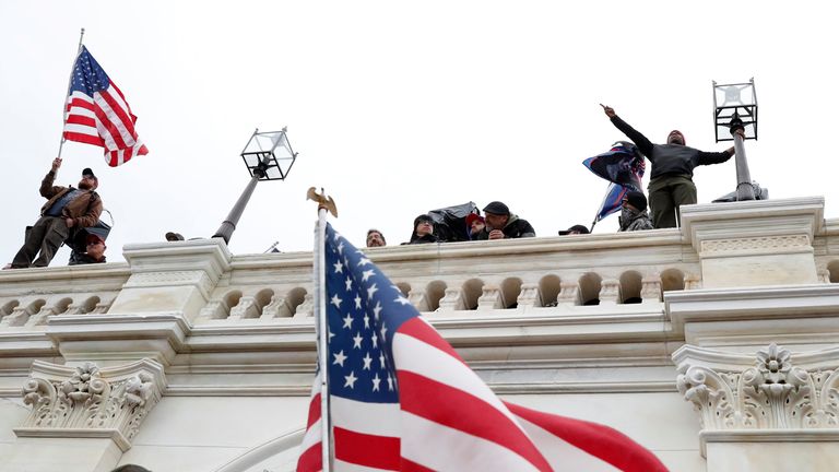 Pro-Trump protesters wave American flags after breaching the Capitol barricades