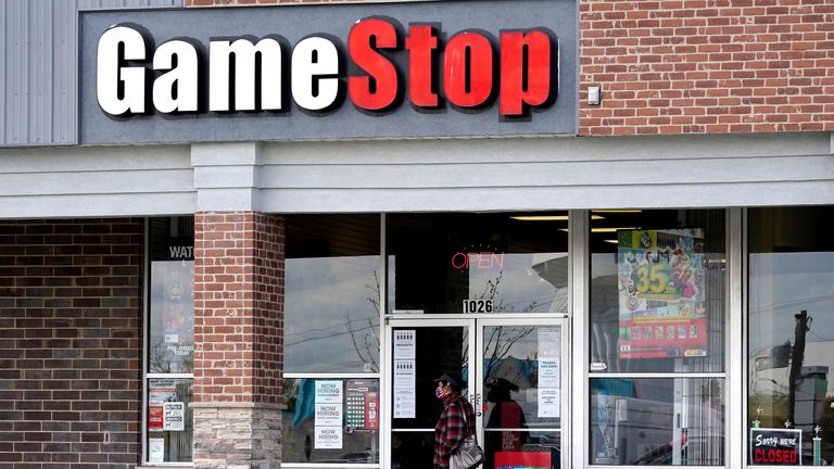 A woman wears a mask as she walks past a GameStop store in Des Plaines, Ill., Thursday, Oct. 15, 2020. GameStop is closing more stores than it originally planned, with the struggling retailer warning of more closures next year. (AP Photo/Nam Y. Huh)