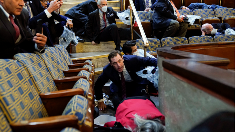 People take shelter in the Chamber gallery as protesters try to break into the Chamber of the Chamber