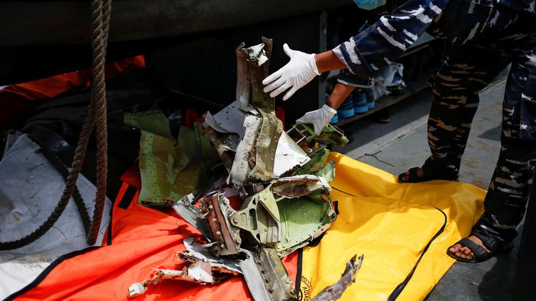 Ein Mitglied der indonesischen Marine inspiziert ein Stück Flugzeugtrümmer