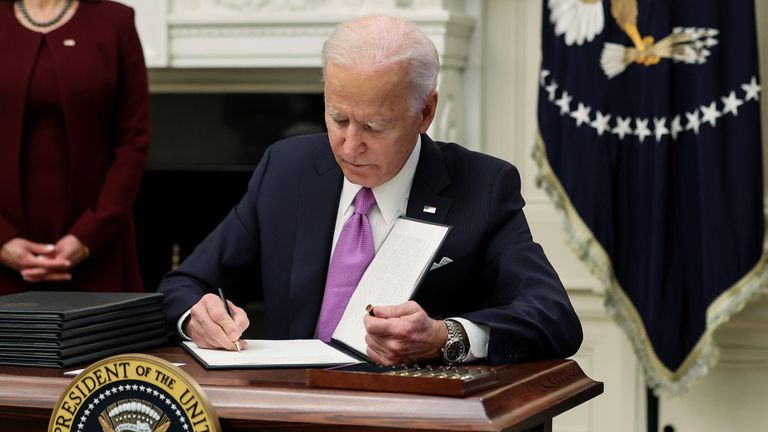 Joe Biden signs an executive order as part of his administration's plans to fight the coronavirus disease