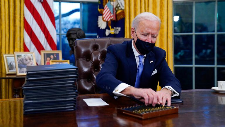 Joe Biden signs his first three executive orders as president. Pic: AP