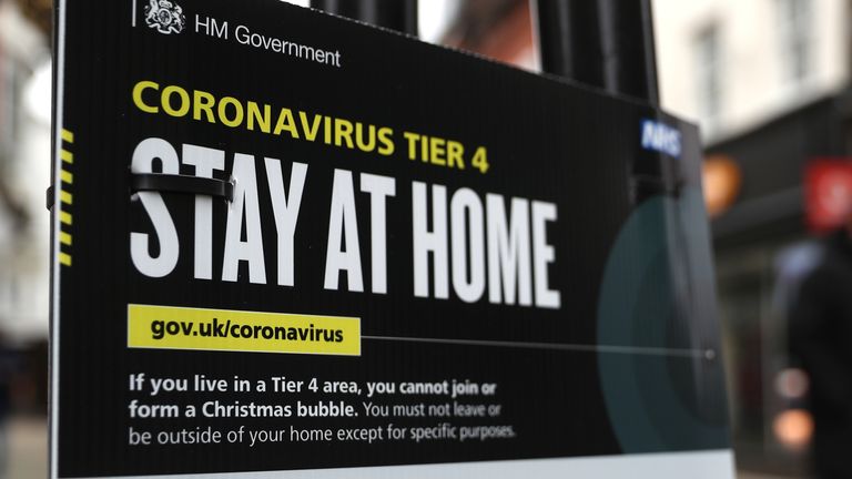 People make their way past a Government coronavirus Tier 4 sign on the High street in Winchester, Hampshire. Millions more people have moved to harsher coronavirus restrictions today as the new tier changes came into force in England.
