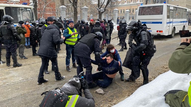 A man being detained by riot police 