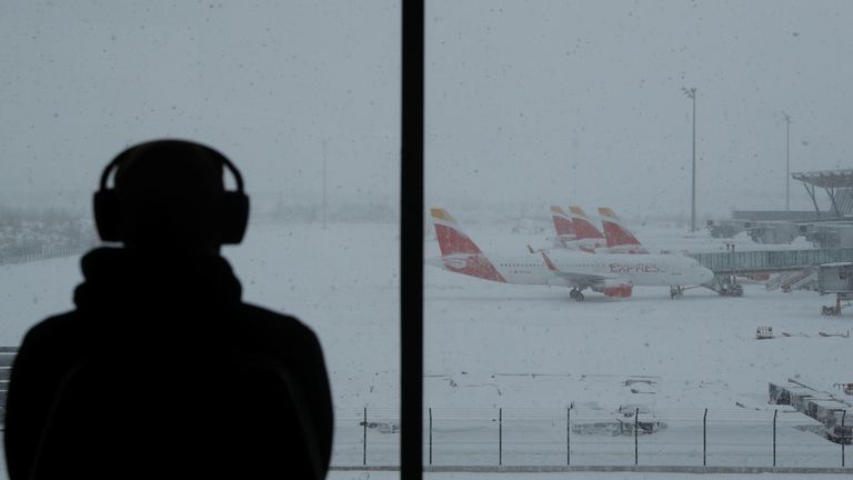 Una persona observa aviones estacionados en el aeropuerto Adolfo Suárez Barajas, que suspende vuelos por fuertes nevadas