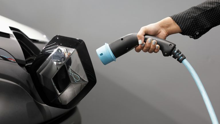 A woman holds a cable to charge up a Renault Kangoo ZE electric utility vehicle at a Renault automobile dealership in Cagnes-Sur-Mer, France, October 22, 2020.