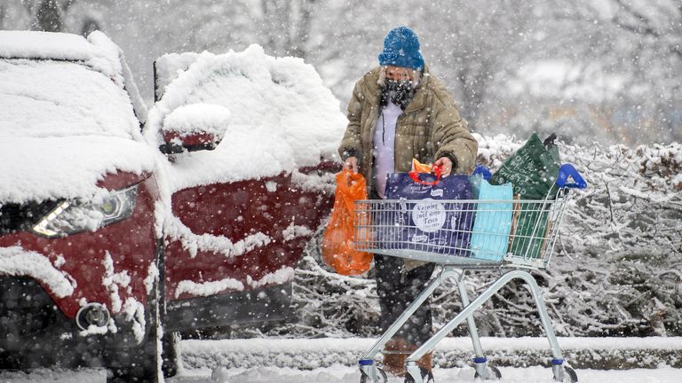 A woman loads shopping into her car as heavy snow falls in Dunstable, Bedfordshire